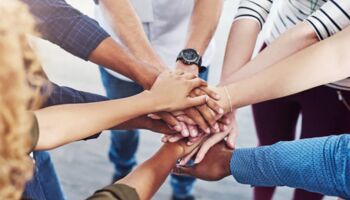 Closeup shot of a group of people joining their hands together in a huddle